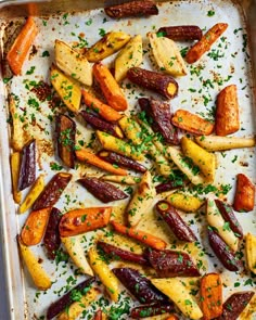 roasted carrots and potatoes on a baking sheet with parsley sprinkled on top