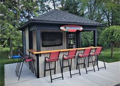 an outdoor bar with red chairs and a television