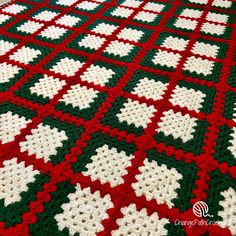 a crocheted blanket with red, white and green squares on top of it