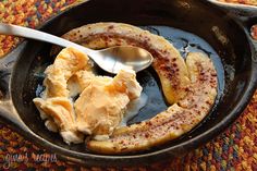 banana slices and ice cream in a cast iron skillet on a colorful tablecloth