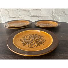 three yellow and brown plates sitting on top of a wooden table