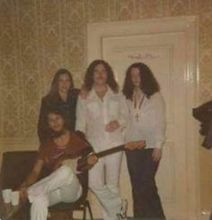 four women posing for a photo in front of a door with a guitar on the floor