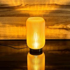 a yellow glass lamp sitting on top of a wooden table next to a wood wall