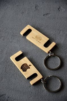 two wooden bottle openers with key chains attached to them on a gray surface,