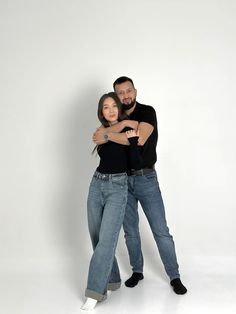 a man and woman hugging each other in front of a white background with their arms around each other