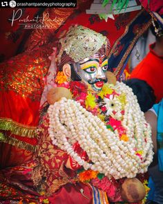 a person dressed up as a god with flowers in their hair and beads around his neck