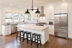 a large kitchen with white cabinets and stainless steel appliances