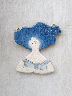 a ceramic brooch with a woman's face and blue hair on the back