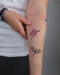 a woman's arm with tattoos on it and two small dragon tattoo designs on the arms