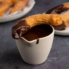 two plates with churros and dipping sauce on them, one is dipped in chocolate