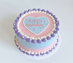 a birthday cake decorated with pink, blue and white icing