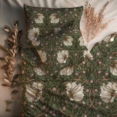 an image of a bed with flowers and leaves on the comforter cover, next to a plant