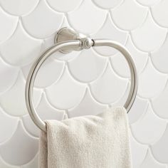 a towel hanging on the side of a wall next to a toilet paper roll and a towel rack