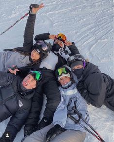 a group of people laying in the snow with skis and goggles on their heads