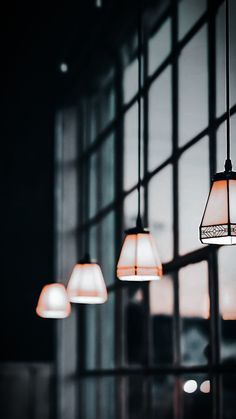 three lamps hanging from the ceiling in front of a window with glass panes on it