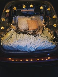 the back of a car with lights in it's trunk and pillows on the bed