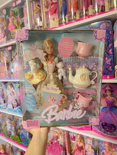 a barbie doll in a box on display at a toy store with other dolls and toys behind it