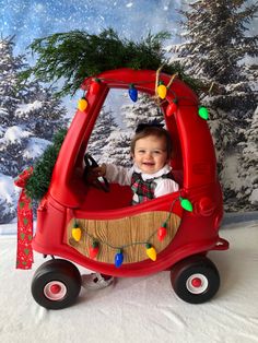 a baby is sitting in a red toy car with christmas lights on it's roof