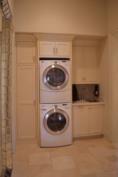 a washer and dryer are in the middle of a kitchen with white cabinets