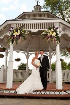 a bride and groom standing in front of a gazebo