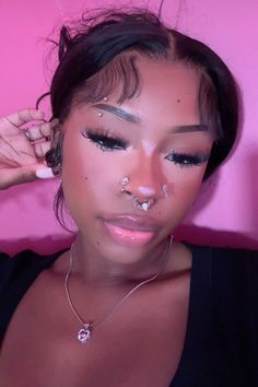 a woman with nose piercings on her nose and wearing a black top is posing for the camera