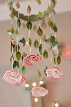 a pink flower mobile hanging from the ceiling in a room with candles and flowers on it