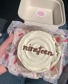 someone holding a cake with the word nineteen on it