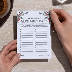 a person holding up a baby name and alphabet race card on top of a table