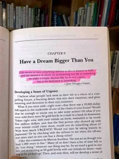 an open book with pink marker on it in front of a bookshelf full of books