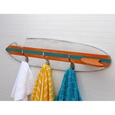 a surfboard mounted to the side of a wall with towels hanging from it's hooks