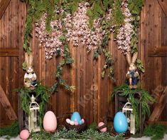 an easter scene with fake eggs and bunnies in front of a wooden wall decorated with greenery