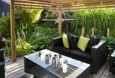 an outdoor living area with couches, tables and plants on the deck in front of it