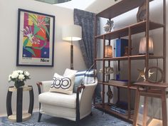 a living room filled with furniture and a book shelf next to a vase full of flowers