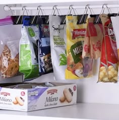 several bags of food are hanging on the wall next to boxes of cookies and muffins