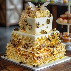 a three tiered cake with bees and flowers on the top is sitting on a table