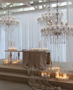 a table topped with lots of candles next to a chandelier filled with lights