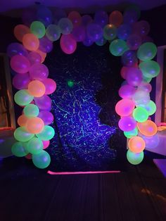 an arch made out of balloons and streamers in the shape of a heart on a dark wood floor