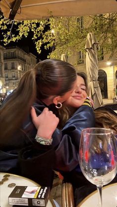 two women hugging each other at an outdoor restaurant