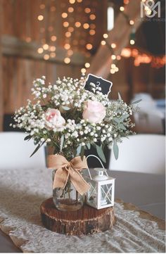 a vase filled with flowers sitting on top of a wooden table next to a small lantern