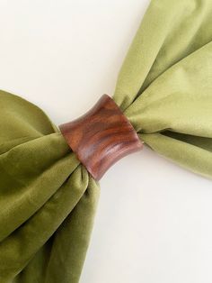 a wooden bow tie on top of a green cloth covered headband with a wood handle