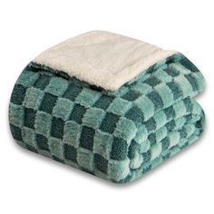 a green and white checkered blanket on top of a bed next to a pillow