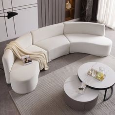 a white couch sitting on top of a living room floor next to a coffee table