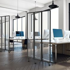 an office with multiple desks and chairs in front of glass partitions that divide the space