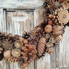 a wreath made out of pine cones and acorns hanging on a wooden door