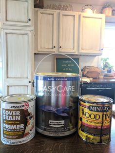 three paint cans sitting on top of a wooden table