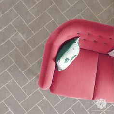 a red chair with a pillow on top of it in the middle of a floor