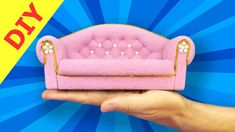 a hand holding a pink couch with pearls on it