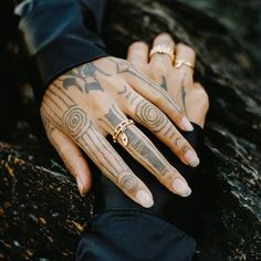 a person with tattoos on their hands holding onto another persons hand and wearing gold rings