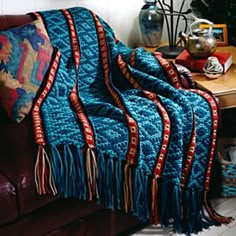 a couch with a blanket on top of it next to a table and vases