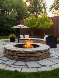 an outdoor fire pit surrounded by grass and trees